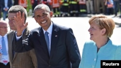 바락 오바마 미국 대통령이 7일 G7 정상회의가 열리는 독일에 도착해 앙겔라 메르켈 총리와 걸으며 손을 들어 보이고 있다.
