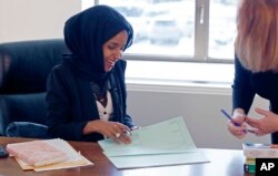 FILE - State Rep. Ilhan Omar (L) confers with another lawmaker in her office two days after the 2017 Legislature convened in St. Paul, Minn.
