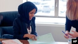 FILE - New state Rep. Ilhan Omar, left, confers with another lawmaker in her office two days after the 2017 Legislature convened in St. Paul, Minn.