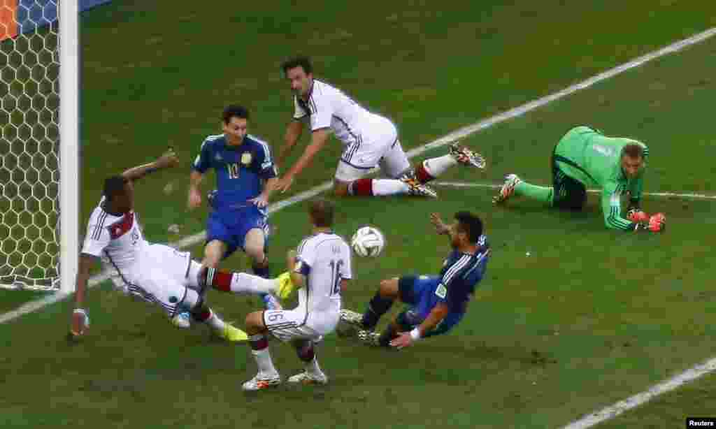 O alemão Jerome Boateng desvia a bola da rota da baliza, enquanto os argentinos Ezequiel Lavezzi e Lionel Messi tentam alcançar o golo, no estádio do Maracanã, Rio de Janeiro, Julho 13, 2014.