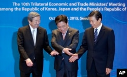 South Korea's Trade, Industry and Energy Minister Yoon Sang-jick, center, tries to hold hands to pose for the media with Japan's Economy, Trade and Industry Minister Motoo Hayashi, left, and China International Trade Representative Zhong Shan.