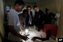 Members of the European Union Election Observation Mission, behind, observe electoral workers count ballots at a polling station at the end of the national elections in Port-au-Prince, Haiti, Oct. 25, 2015.