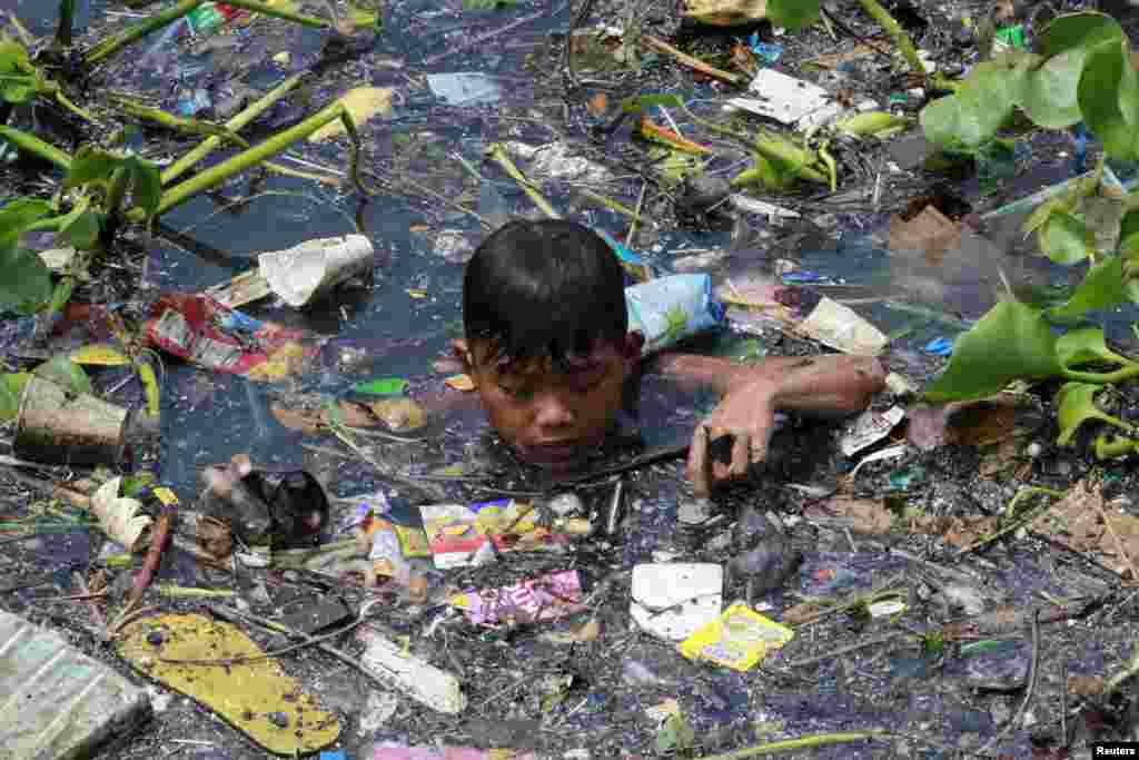 
Một cậu bé thu nhặt những vật liệu tái chế trên một con sông ô nhiễm ở thành phố Navotas, phía bắc Manila, Philippines.