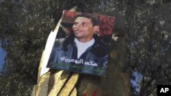 In this Jan. 19, 2011 file photo youths gather below the portrait of Mohamed Bouazizi in Sidi Bouzid, central Tunisia. Bouazizi's death gave rise to a protest movement that spread across the Middle East.(AP Photo/Salah Habibi)