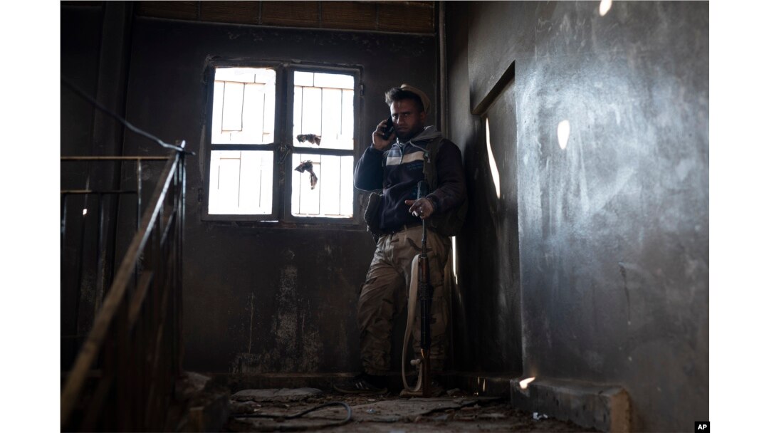 A U.S.-backed Syrian Democratic Forces fighter talks on his phone inside a building used as a temporary base near the last land still held by Islamic State militants in Baghouz, Syria, Feb. 18, 2019.