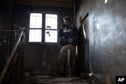 A U.S.-backed Syrian Democratic Forces fighter talks on his phone inside a building used as a temporary base near the last land still held by Islamic State militants in Baghouz, Syria, Feb. 18, 2019.