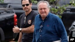 A federal police officer escorts Brazil's former Agriculture Minister Wagner Rossi into Federal Police headquarters in Sao Paulo, Brazil, March 29, 2018. 