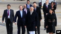 Indian Prime Minister Narendra Modi (c) is greeted by Minister of State for the Foreign and Commonwealth Office, Hugo Swire (l) and MP Priti Patel as he arrives at Heathrow Airport, London, for an official three day visit, Nov. 12, 2015. 