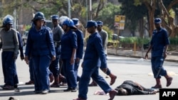 A protester lies unconsciously on the ground after being beaten by police near Unity Square in Harare on August 16, 2019. - Riot police in Zimbabwe fire teargas and beat demonstrators on August 16 during a crackdown on opposition supporters who have taken