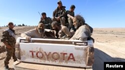Islamic State fighters sit on a pickup truck while being held as prisoners by fighters of the Syrian Democratic Forces near Ash Shaddadi, Hasakah province, Syria, Feb. 18, 2016.