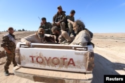 FILE - Islamic State fighters sit on a pickup truck while being held as prisoners by fighters of the Syrian Democratic Forces near Ash Shaddadi, Hasakah province, Syria, Feb. 18, 2016.