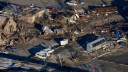 In a view from this aerial photo, people walk amidst destruction from a recent tornado in downtown Mayfield, Ky., Sunday, Dec. 12, 2021. (AP Photo/Gerald Herbert)