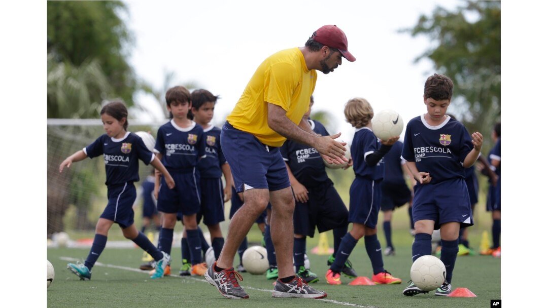 In this 2014 photo, Lee Santamaria, front, teaches children during a soccer camp held in Miami, Florida.