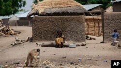 FILE - A woman sits outside her home in Chibok, Nigeria, May 19, 2014. Boko Haram fighters were overrunning villages near the northeastern Nigerian town, forcing hundreds of people to flee as the insurgents looted and burned in the area where nearly 300 schoolgirls were kidnapped in 2014, local leaders said, Nov. 22, 2016. 