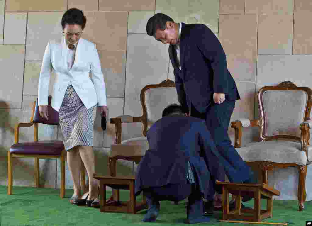 An aide helps Chinese President Xi Jinping tie his shoe, with his wife Peng Liyuan standing beside, after visiting Rajghat, the memorial to India&#39;s independence leader Mohandas Gandhi, more popularly called Mahatma Gandhi, in New Delhi, India. 