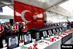 FILE - Airport employees attend a ceremony for their friends, who were killed in an attack at the airport, at the international departure terminal of Ataturk airport in Istanbul, Turkey, June 30, 2016.