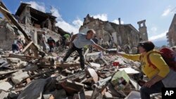 Para petugas mencari penyintas di bawah puing-puing akibat gempa di kota Amatrice, Italia tengah (24/8). (AP/Alessandra Tarantino)