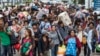 FILE - Cambodian migrant workers carry their belongings as they walk to cross the border at Aranyaprathet in Sa Kaew, June 15, 2014.