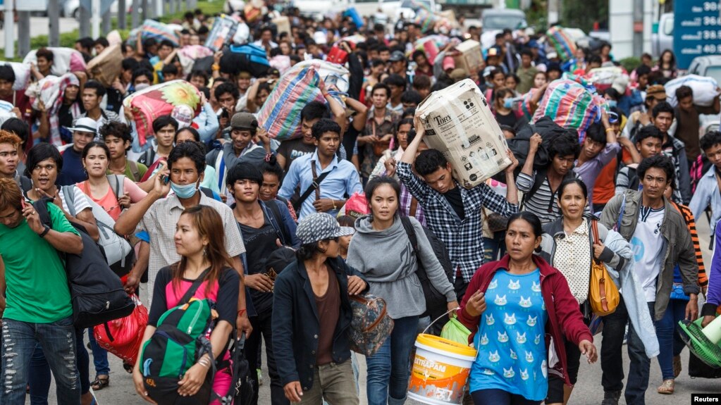 FILE - Cambodian migrant workers carry their belongings as they walk to cross the border at Aranyaprathet in Sa Kaew, June 15, 2014.