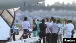 Chinese activists detained after landing on a disputed island are escorted by airport officials as they board a flight to Hong Kong, in this photo taken by Kyodo August 17, 2012. 