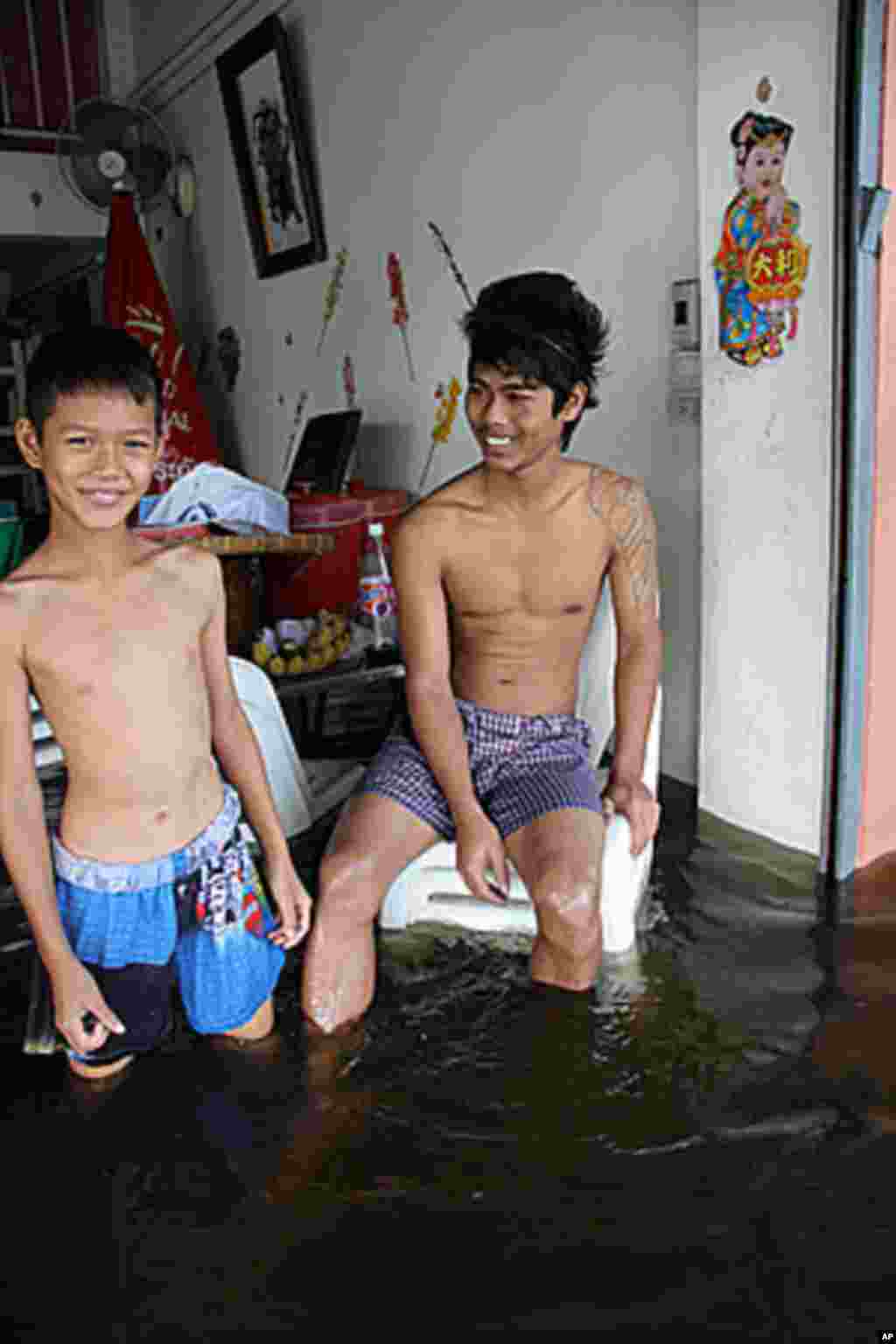 A restaurant owner lives in his flooded restaurant with his children, Bangkok, Thailand, October 28, 2011. (VOA)