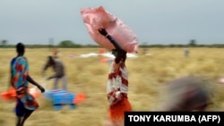Collectent d'aide alimentaire larguée d'un avion dans des sacs en plastique sur une zone de largage dans un village du comté d'Ayod, au Sud-Soudan, le 6 février 2020. (Photo: AFP/TONY KARUMBA)