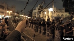 Egyptian protesters stand in front of barbed wire beyond the presidential palace in Cairo, December 4, 2012.