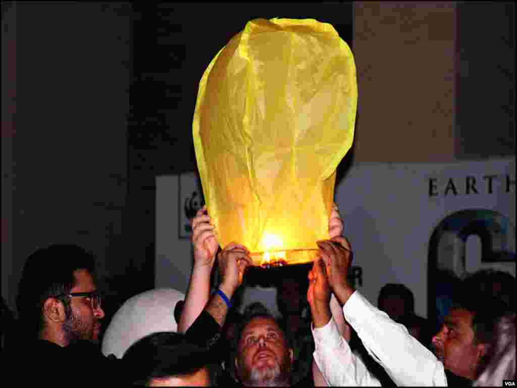 تقریب میں شریک افراد لالٹین نما غبارے ہوا میں چھوڑرہے ہیں