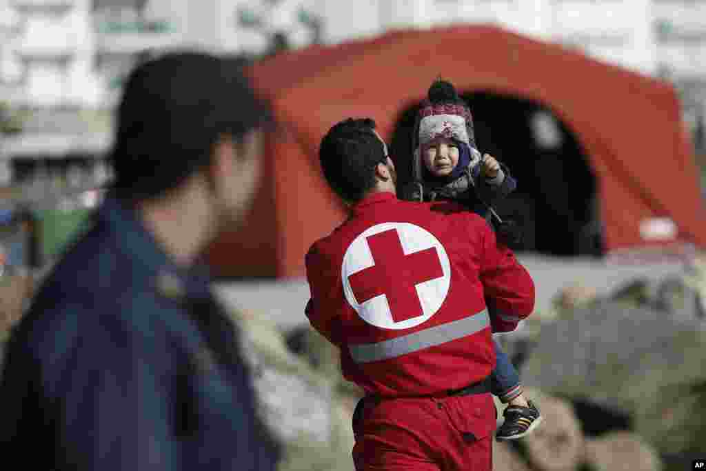 A Red Cross volunteer carries a child just disembarked from a crippled freighter carrying hundreds of refugees trying to migrate to Europe, at the coastal Cretan port of Ierapetra, Greece.