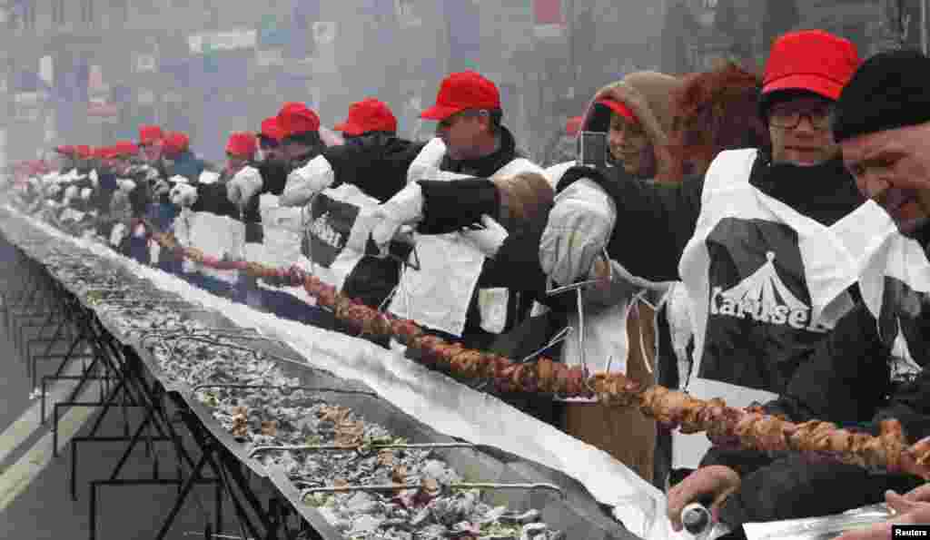 People cook a giant 150-meter-long "shashlik" meal in Kyiv, Ukraine. Participants broke the national record of the longest shashlik cooked during the event. Shashlik is a variety of skewered meat traditionally eaten in the Commonwealth of Independent States (CIS) region.