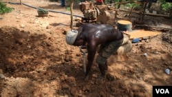 A miner uses a shovel to haul dirt at the Atunso Cocoase small-scale mine in Atunso, Ghana, Oct. 16, 2014. (Chris Stein/VOA)