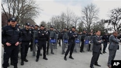 Riot police stand at the entrance of parliament in Ankara, as dozens of Turkish women stage a demonstration to protest the rape and killings of children and women in Turkey, April 14, 2011