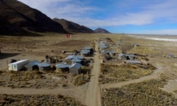 Residents walk along a dirt road in the Urus del Lago Poopo indigenous community, which sits along the salt-crusted former shoreline of Lake Poopo, in Punaca, Bolivia, Monday, May 24, 2021.