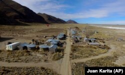 Residents walk along a dirt road in the Urus del Lago Poopo indigenous community, which sits along the salt-crusted former shoreline of Lake Poopo, in Punaca, Bolivia, Monday, May 24, 2021.