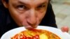 FILE - Chef Bobby Chinn sips from a bowl of Laksa, a dish popular in Singapore hawker centres, while posing for a photo in Singapore. 