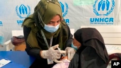 FILE - A Rohingya refugee gets vaccinated against COVID-19 in Cox's Bazar, Bangladesh, Aug.10, 2021.