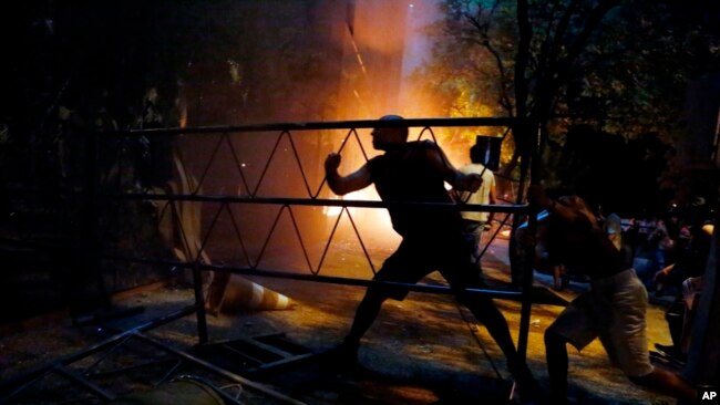 La gente golpea una barrera en el edificio del congreso durante los enfrentamientos entre la policía y los manifestantes que se oponen a una enmienda constitucional aprobada que permitiría la elección de un presidente a un segundo periodo, en Asunción, Paraguay, el 31 de marzo de 2017.