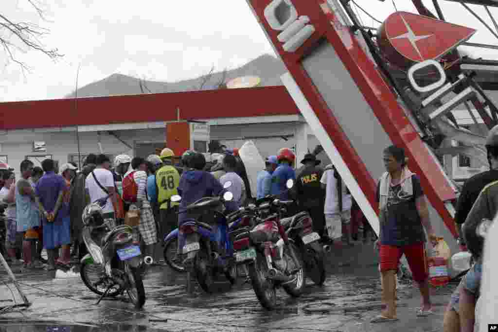 Para penyintas memompa bahan bakar dari sebuah pom bensin yang rusak di Tacloban, Filipina (14/11). (AP/Bullit Marquez)