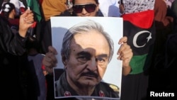 A woman holds a portrait of former Libyan army officer Khalifa Haftar, during a rally supporting Haftar, in Benghazi, Libya, Aug. 1, 2014.