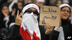 A Bahraini female Shi'ite protester holds a sign reading: "our demands are for country" during a rally in the village of Diraz, West of Manam, July 1, 2011