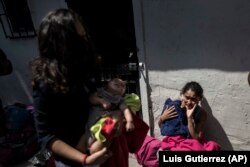 Central American mothers and children who are traveling with a caravan of migrants, wait to figure out their night's accommodations at a shelter after arriving to Tijuana, Mexico, Wednesday, April 25, 2018.