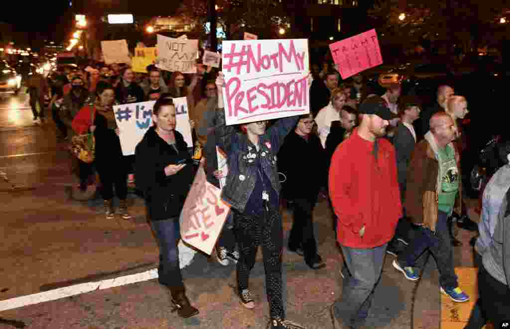 Protesters holds up signs in opposition of Donald Trump's presidential election victory as they march from Jefferson Square Park in Louisville, Kentucky, Nov. 10, 2016. 