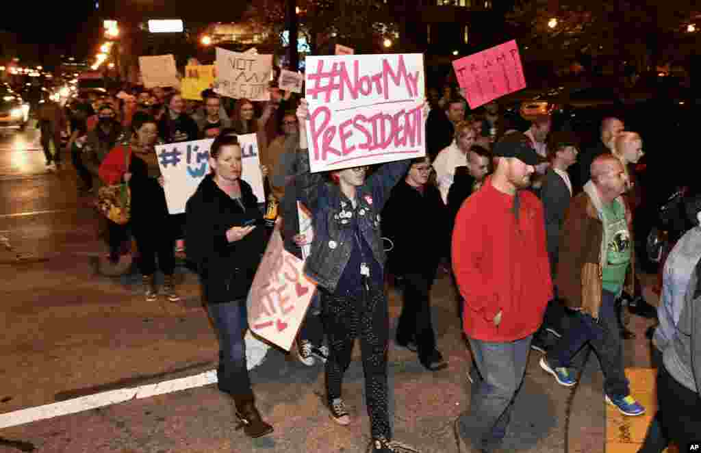 Para demonstran di Louisville, Kentucky, memegang papan bertuliskan tulisan yang menolak kemenangan Donald Trump pada pemilihan presiden (10/11).&nbsp;(AP Photo/Timothy D. Easley)