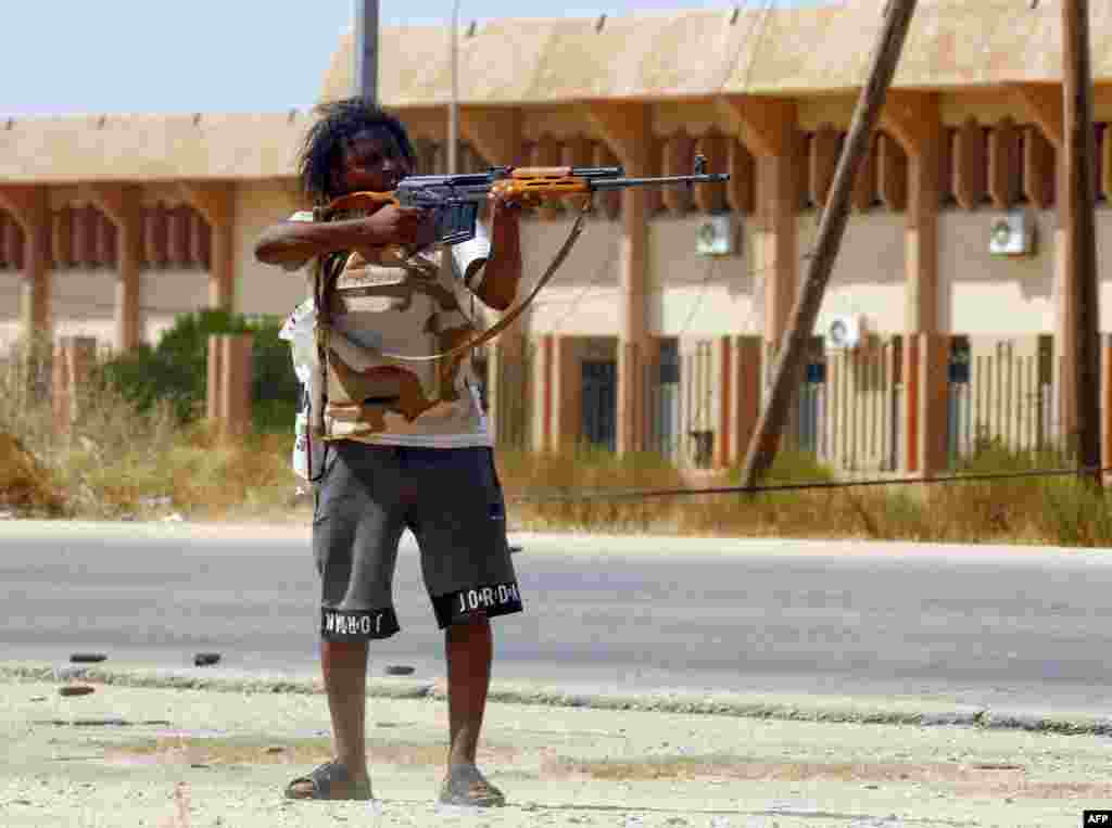 A fighter loyal to the U.N.-recognized Government of National Accord (GNA) points his gun toward enemy lines during clashes with forces loyal to strongman Khalifa Haftar, in Espiaa, about 40 kilometers (25 miles) south of the Libyan capital Tripoli, Aug. 21, 2019.