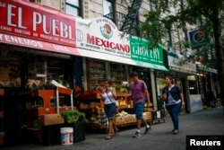 FILE - People pass by a Mexican grocery store in Harlem, New York, Aug. 10, 2014.