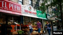 FILE - People pass by a Mexican grocery store in Harlem, New York, Aug. 10, 2014.