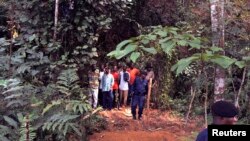 Des policiers encadrent un groupe d’homme près des tombes nouvellement creusées dans la jungle à Ndenga Mongo, province de Kasaï, RDC, 4 août 2007. 