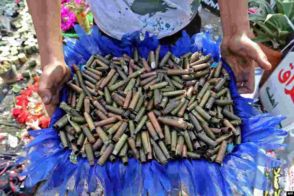 An Iraqi anti-government demonstrator shows a basket full of empty bullet cartridges found in the capital Baghdad&#39;s Tahrir Square.