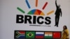 FILE - A delegate walks past a BRICS logo ahead of the 10th BRICS Summit, in Sandton, South Africa. 