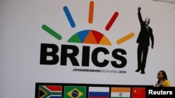 FILE - A delegate walks past a BRICS logo ahead of the 10th BRICS Summit, in Sandton, South Africa, July 24, 2018. 